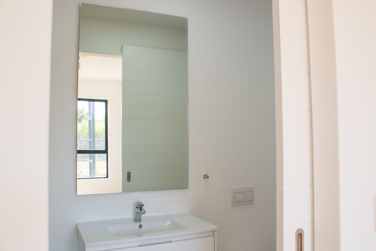 A clean, modern bathroom featuring a sleek vanity with an integrated basin, chrome mixer tap, and a large wall-mounted mirror.