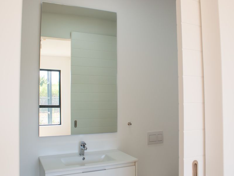 A clean, modern bathroom featuring a sleek vanity with an integrated basin, chrome mixer tap, and a large wall-mounted mirror.