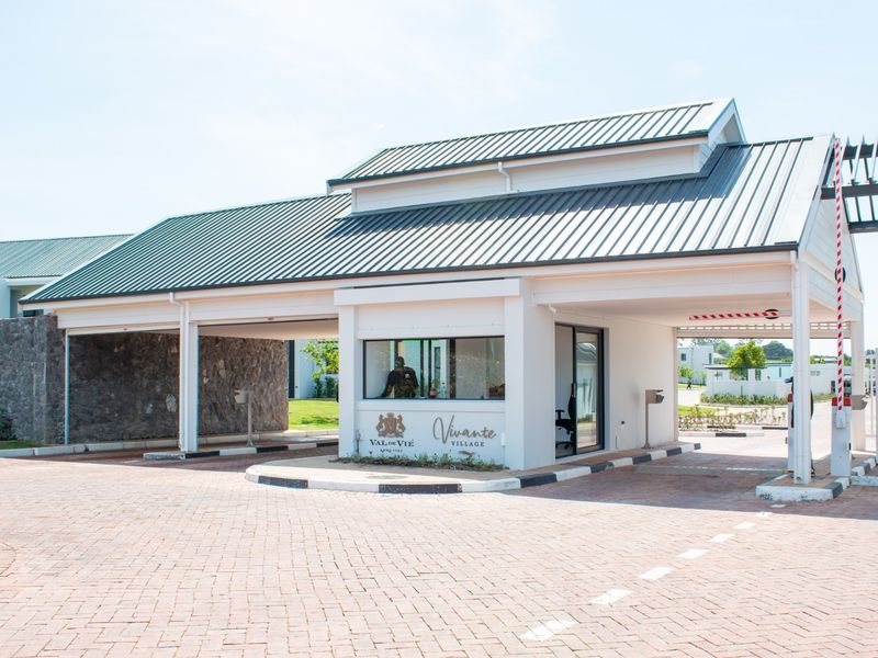 A well-maintained security gatehouse entrance for the residential complex, featuring a paved driveway, boom gate access, and modern architectural finishes.