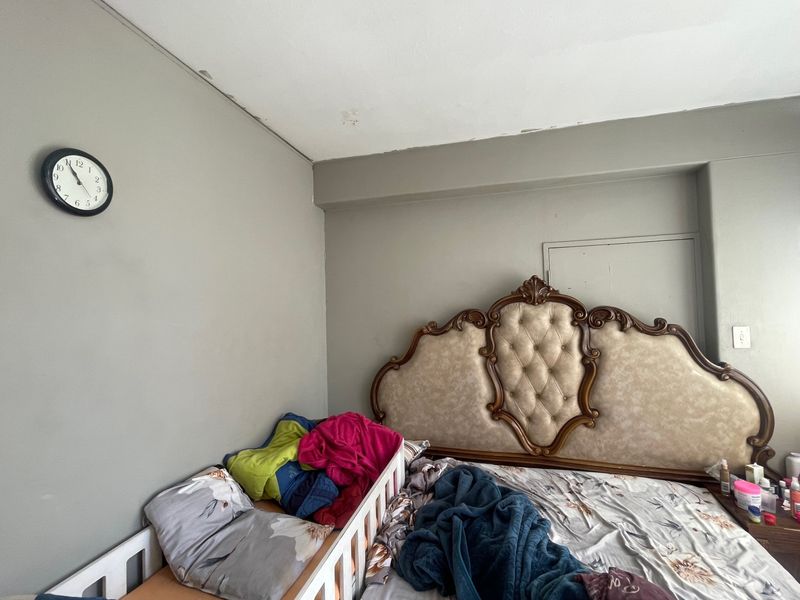 A bedroom featuring neutral wall tones, requiring minor cosmetic repairs to the ceiling and wall plaster to restore its finish.