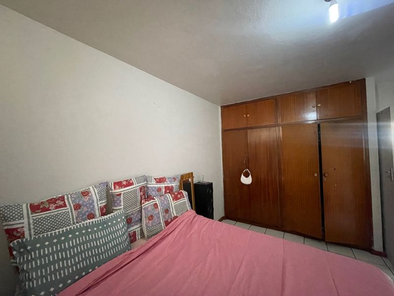 A bedroom featuring built-in wooden wardrobes and tiled flooring, offering a functional space with potential for cosmetic updates.