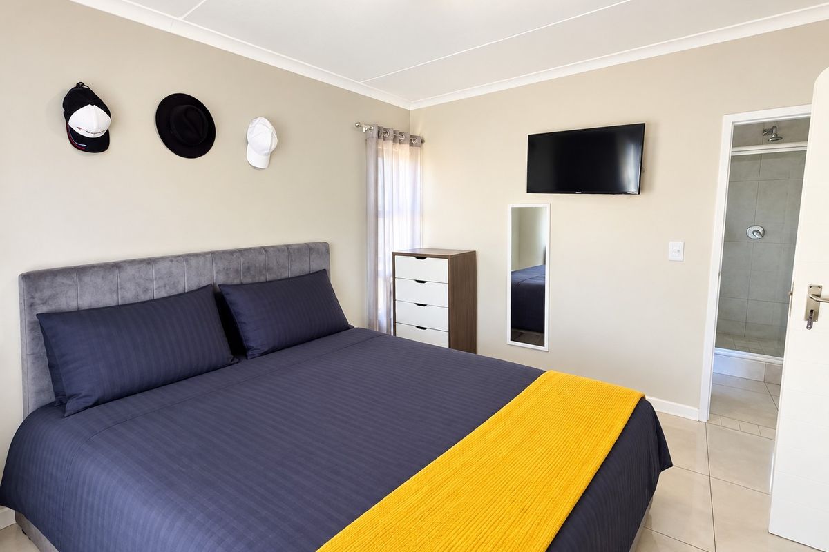 A well-maintained bedroom featuring neutral wall tones, tiled flooring, and direct access to an en-suite bathroom.