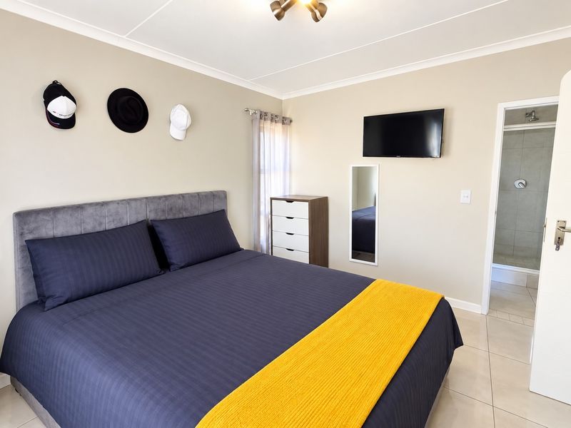 A well-maintained bedroom featuring neutral wall tones, tiled flooring, and direct access to an en-suite bathroom.