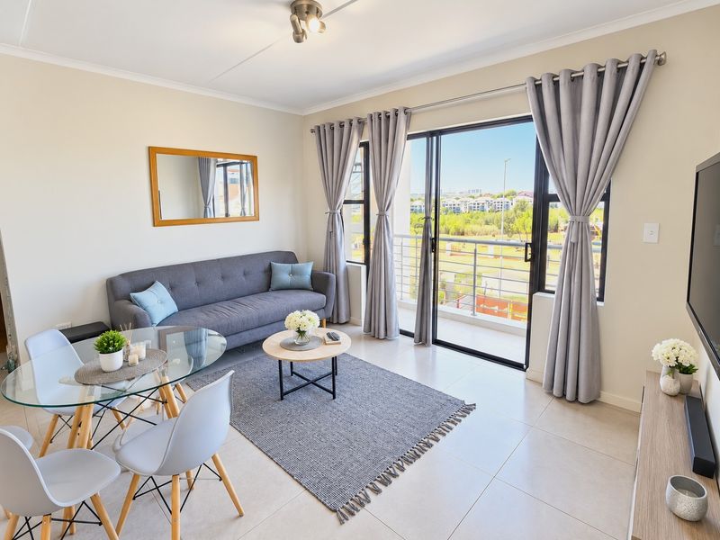 Bright open-plan living area featuring tiled floors and a sliding glass door leading to a balcony with scenic views.