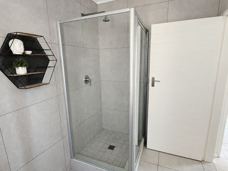 Modern bathroom featuring a glass-enclosed shower with grey floor-to-ceiling tiling and a clean, contemporary finish.