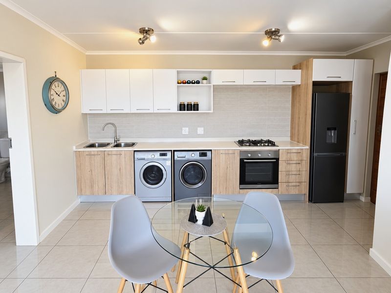 Modern kitchen featuring light wood and white cabinetry, gas hob, electric oven, integrated sink, and tiled flooring in a clean, well-maintained space.