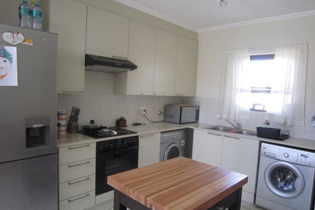A functional kitchen featuring built-in cabinetry, a gas hob with extractor, integrated oven, and a double sink with tiled flooring and backsplash.