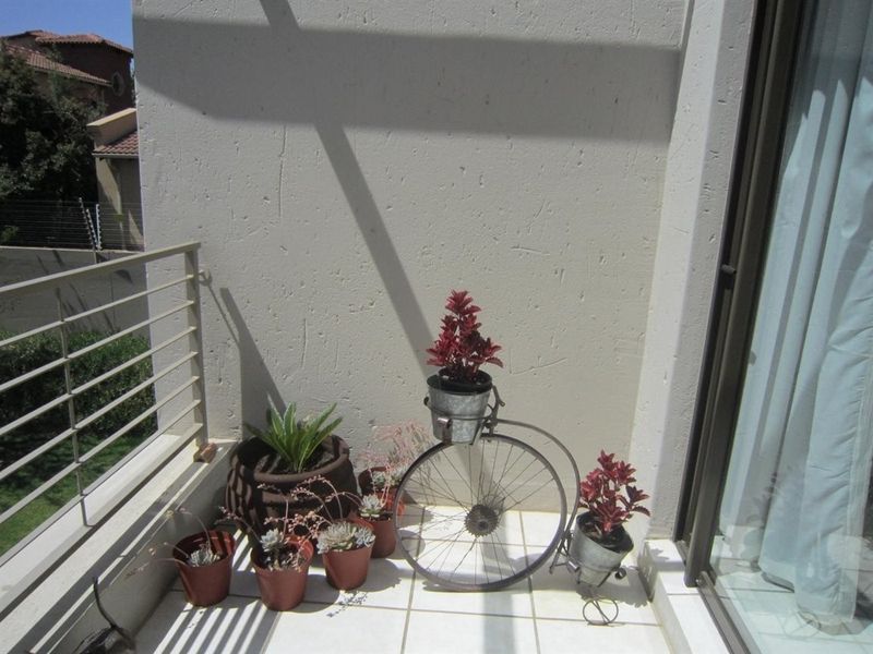 A compact balcony featuring tiled flooring and a metal balustrade, accessible via a sliding glass door.