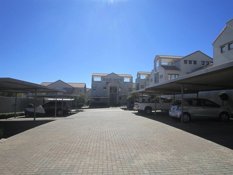 Exterior view of the apartment complex featuring a paved driveway and covered parking bays for residents.