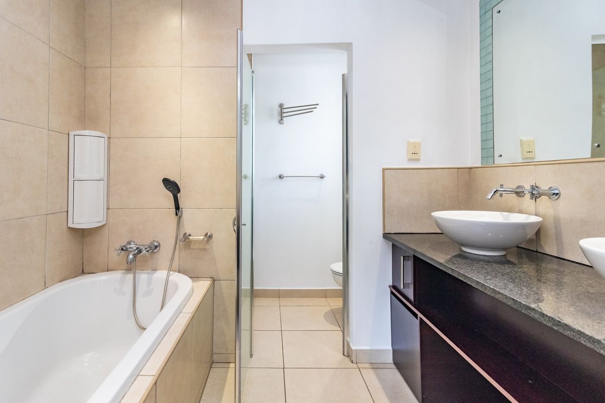 A functional bathroom featuring a built-in bathtub, separate shower enclosure, and a double vanity with stone countertops and vessel sinks.
