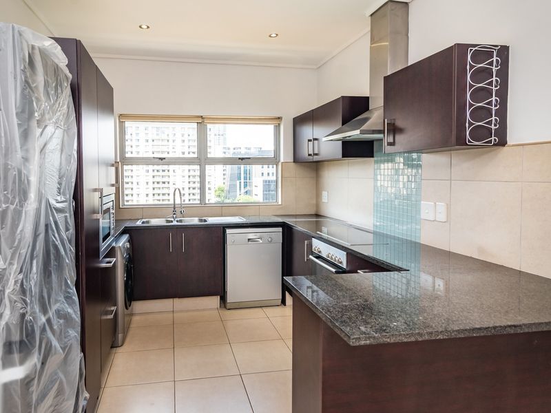 Modern kitchen featuring dark wood cabinetry, granite countertops, integrated appliances, and a tiled backsplash, offering a clean and functional workspace.