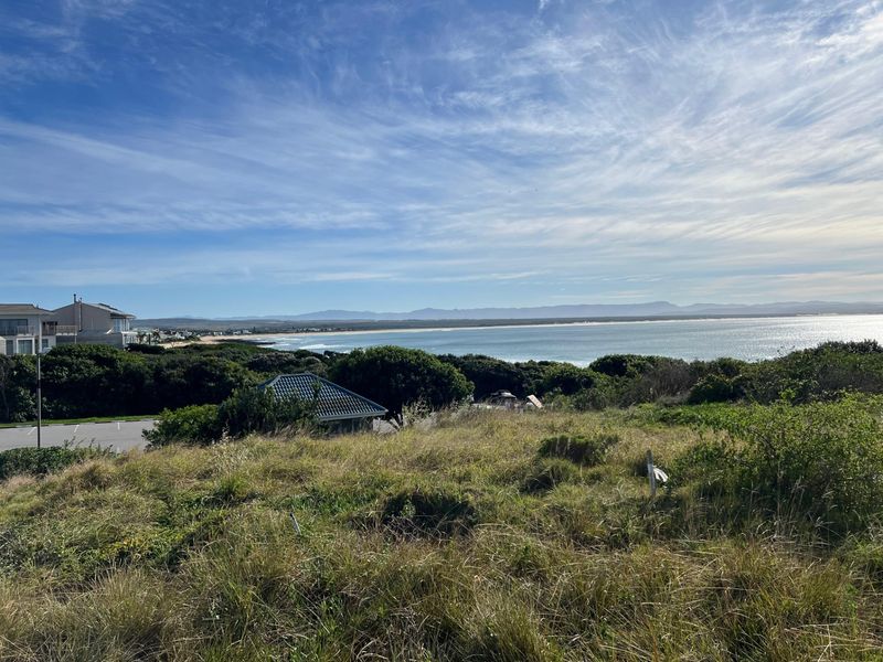 A scenic view overlooking the coastline, ocean, and distant mountains from the vacant residential land.