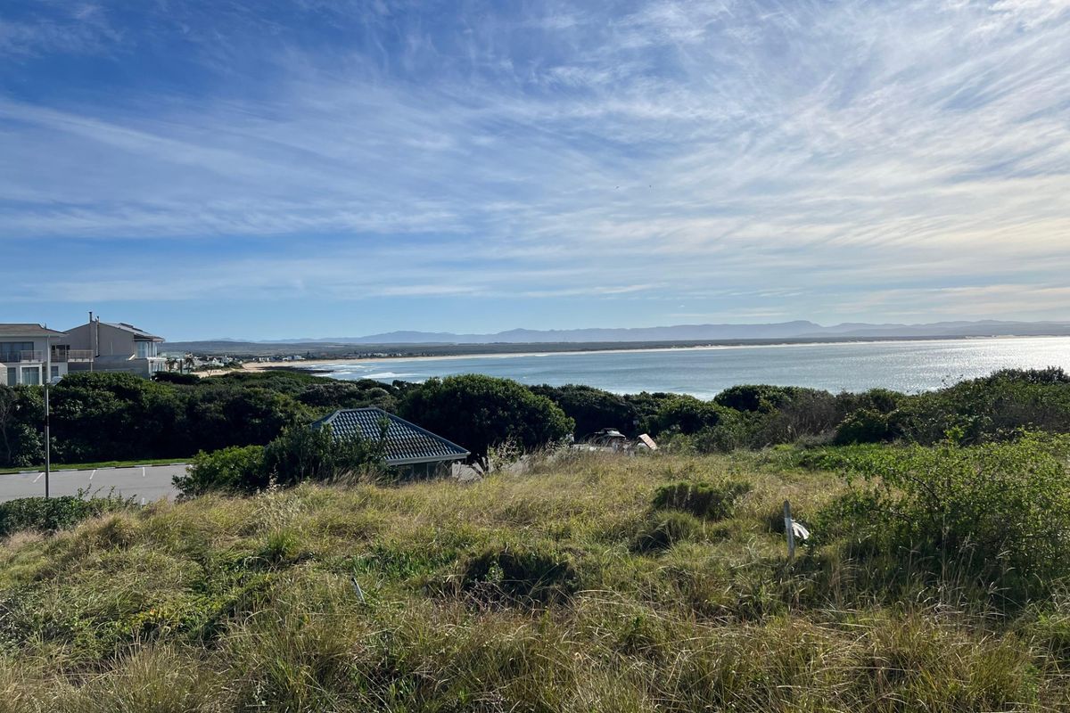 A scenic view overlooking the coastline, ocean, and distant mountains from the vacant residential land.