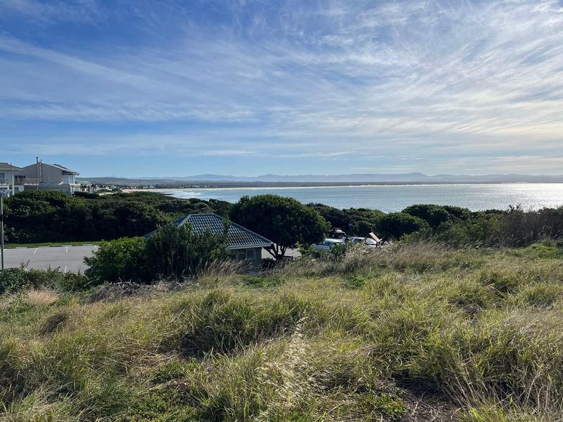 A scenic elevated view overlooking the coastline, ocean, and surrounding natural landscape from the vacant residential property.