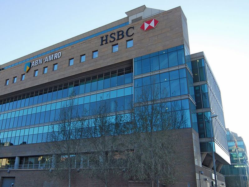 A modern commercial office building featuring extensive glass curtain walling and stone facade cladding with prominent corporate signage.