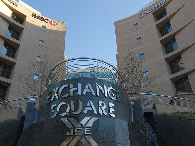 Exterior view of the Exchange Square commercial building complex featuring stone facades, prominent corporate signage, and a central water feature.
