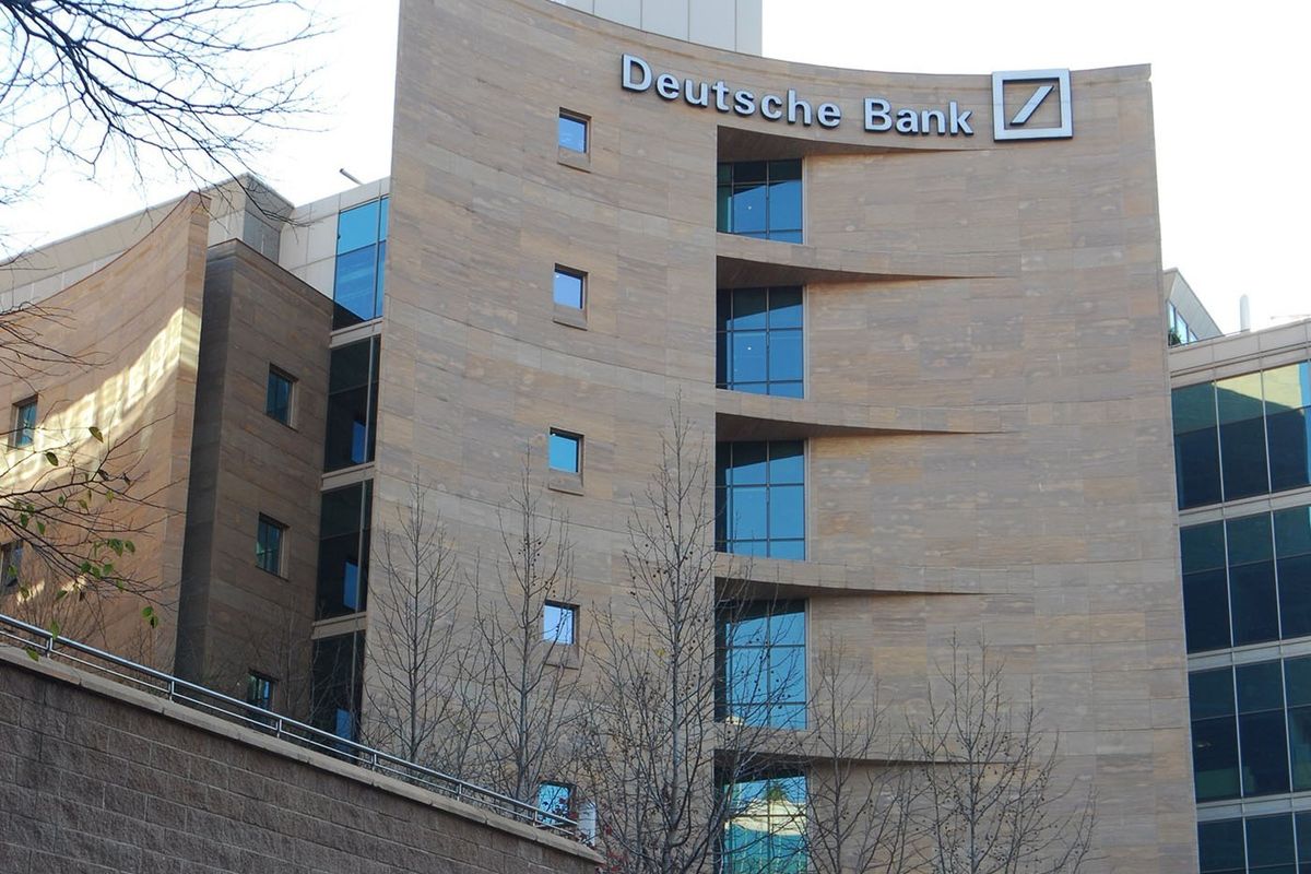 Exterior view of a modern commercial office building featuring a stone facade, large glass windows, and prominent corporate signage.