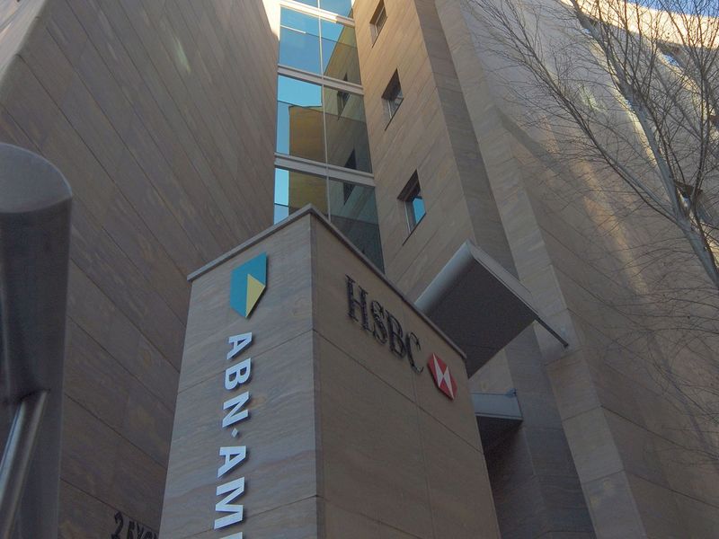 Low angle view of a modern commercial building facade featuring stone cladding, glass windows, and prominent corporate signage.