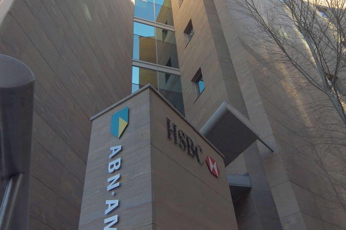 Low angle view of a modern commercial building facade featuring stone cladding, glass windows, and prominent corporate signage.