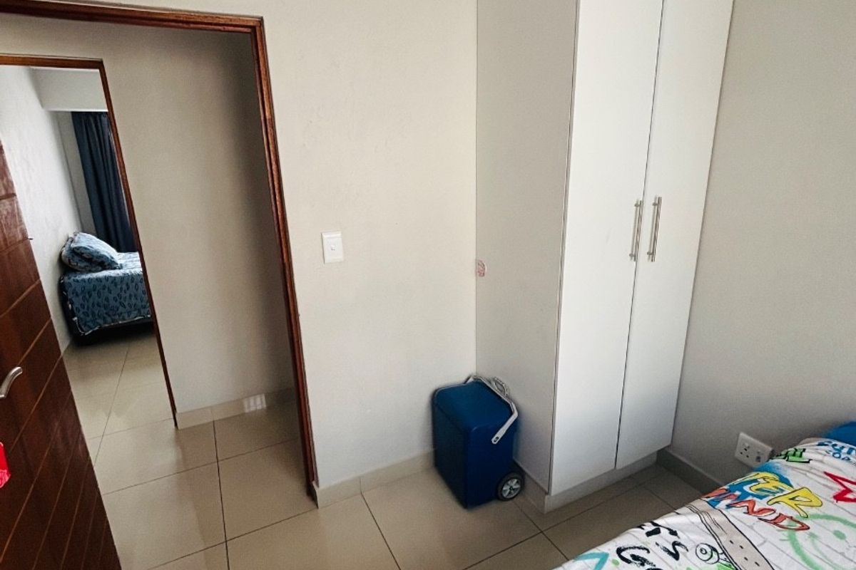 A bedroom featuring tiled flooring, a built-in wardrobe, and a doorway leading to an adjacent room.