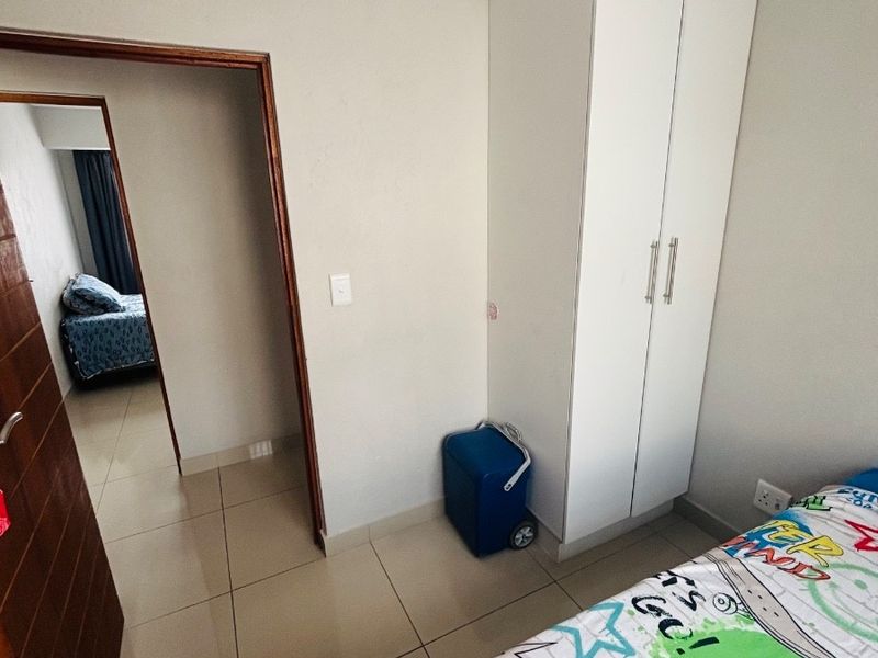A bedroom featuring tiled flooring, a built-in wardrobe, and a doorway leading to an adjacent room.