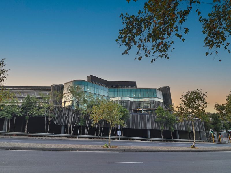 Modern commercial office building featuring a striking glass facade and contemporary vertical slat cladding, viewed from the street level.