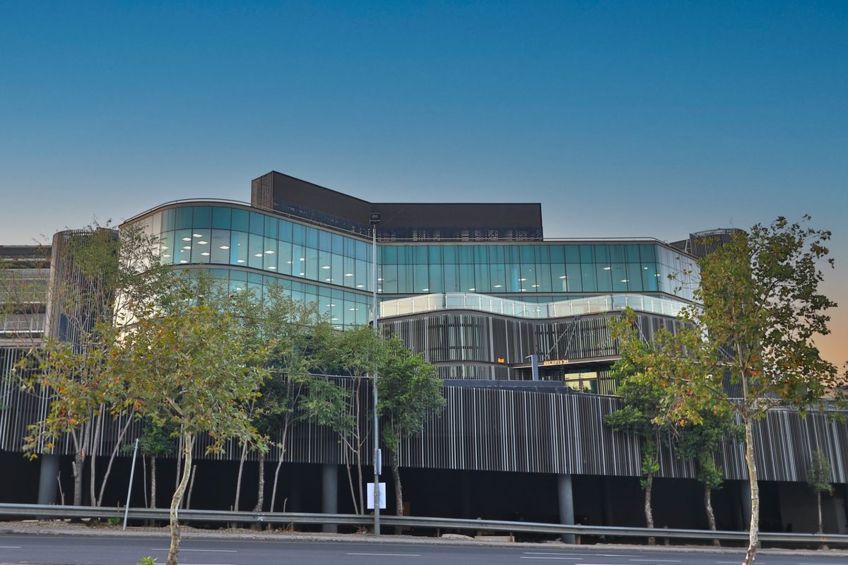 Modern commercial office building featuring a striking glass curtain wall, architectural louvred screening, and a prominent ground-level reception entrance.