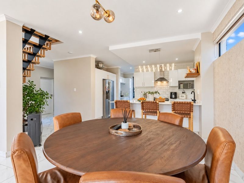 Modern open-plan living and dining area featuring a sleek kitchen with built-in appliances, a central island, and a contemporary staircase.