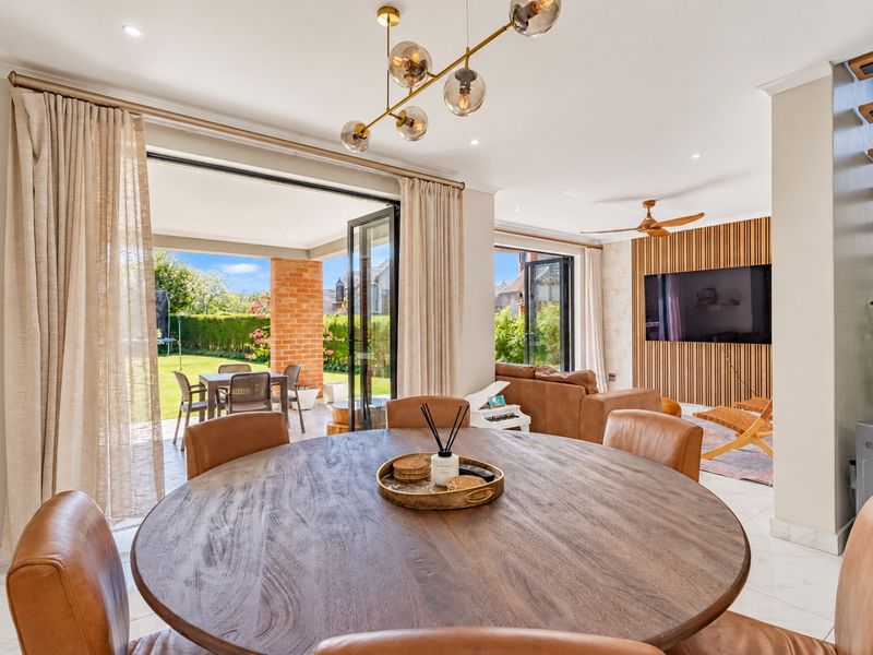 Spacious open-plan living and dining area featuring modern tiled floors, a feature timber slat wall, and seamless indoor-outdoor flow through large bi-fold doors.