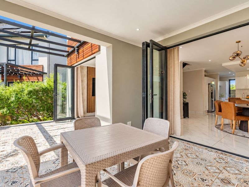 A spacious covered patio featuring decorative floor tiles and bi-fold doors that provide seamless indoor-outdoor flow to the open-plan living and dining area.