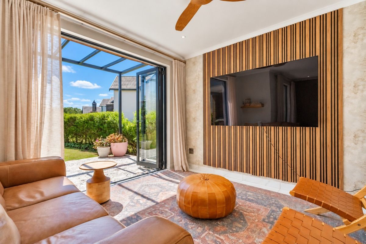 Modern living room featuring a stylish timber slat feature wall, ceiling fan, and seamless indoor-outdoor flow through bi-fold doors to the patio.