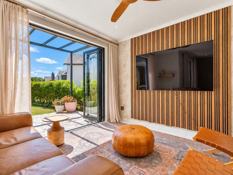 Modern living room featuring a stylish timber slat feature wall, ceiling fan, and seamless indoor-outdoor flow through bi-fold doors to the patio.