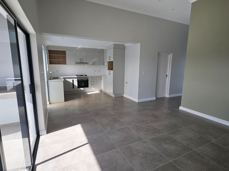 Spacious open-plan living area featuring a modern kitchen with built-in cabinetry, integrated appliances, and large sliding doors leading to an outdoor space.