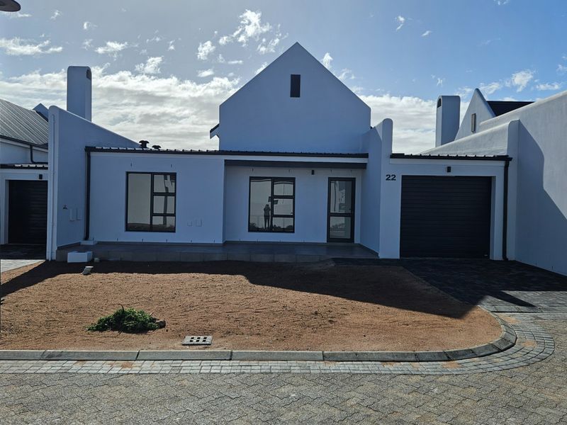 Modern front elevation of a residential house featuring a paved driveway, integrated garage, and clean white facade with contemporary aluminum window frames.
