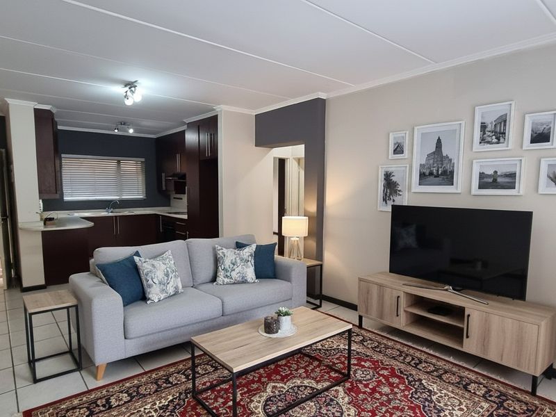 An open-plan living area featuring a modern kitchen with dark cabinetry, tiled floors, and a seamless flow into the comfortable lounge space.