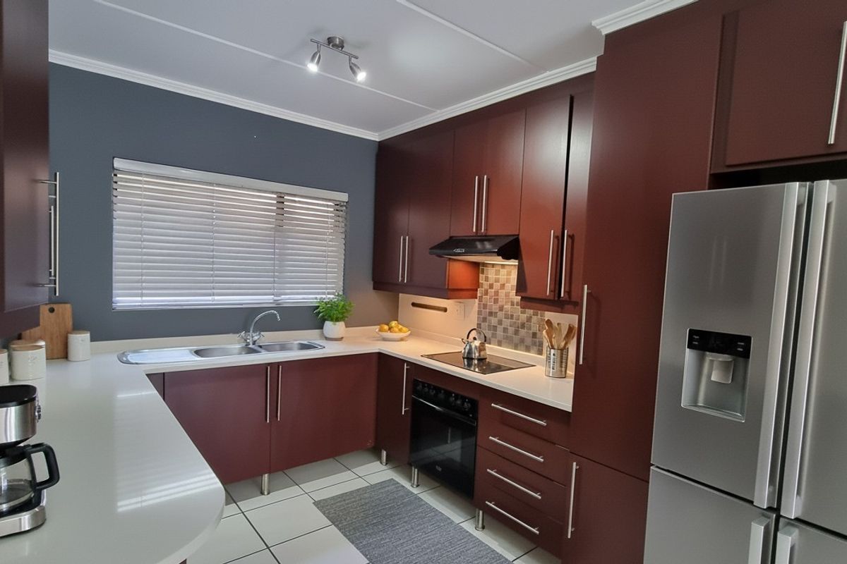 Modern kitchen featuring dark wood cabinetry, stone countertops, integrated appliances, and tiled flooring with a functional layout.