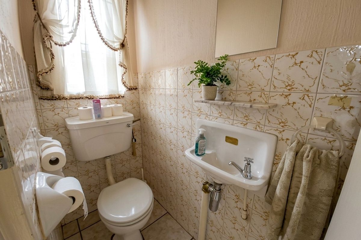Compact guest bathroom featuring a wall-mounted basin, toilet, and decorative tiled finishes.