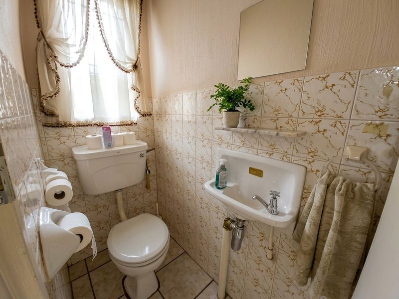 Compact guest bathroom featuring a wall-mounted basin, toilet, and decorative tiled finishes.