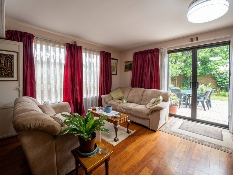 A bright living room featuring polished hardwood flooring and large sliding glass doors that provide direct access to the outdoor patio area.