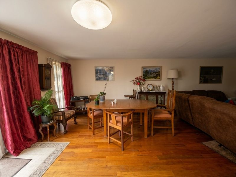 A spacious living and dining area featuring warm hardwood flooring and a central flush mount light fixture, offering a comfortable and functional layout.