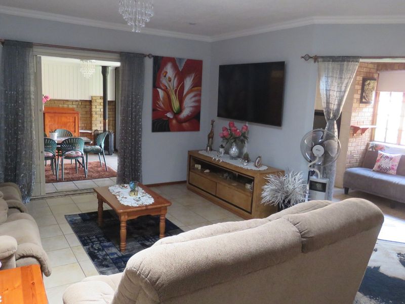 Spacious living room featuring tiled flooring, coved ceilings, and direct access to an adjoining patio area through sliding glass doors.