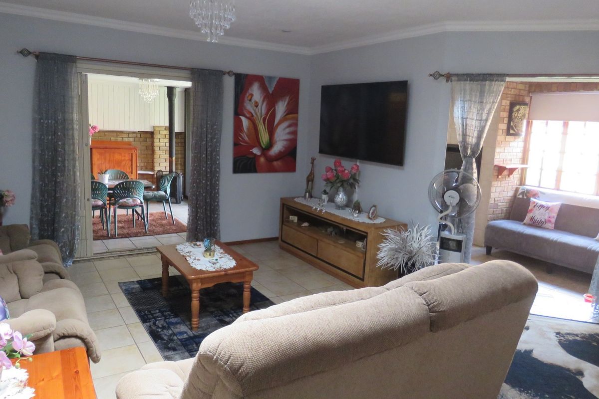 Spacious living room featuring tiled flooring, coved ceilings, and direct access to an adjoining patio area through sliding glass doors.