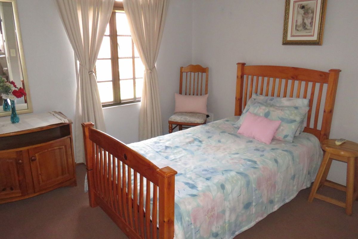 A standard bedroom featuring carpeted flooring and a timber-framed window, providing a functional and lived-in space.