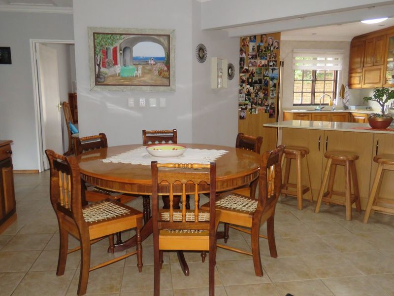 Open plan dining and kitchen area featuring tiled floors, wooden cabinetry, and a functional kitchen island with breakfast bar seating.