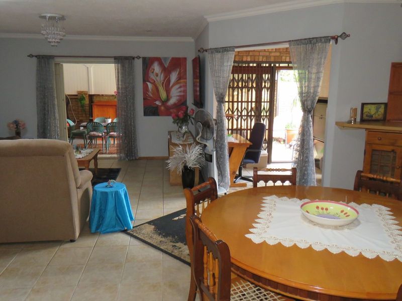 Open plan living and dining area featuring tiled flooring, recessed lighting, and direct access to an outdoor patio through sliding security gates.