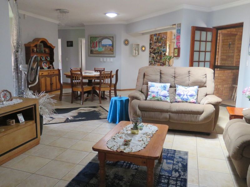 Spacious open-plan living and dining area featuring neutral tiled flooring and direct access to an adjacent room through a classic wooden french door.