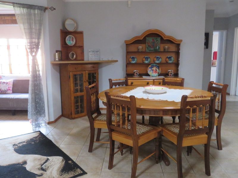 A dining area featuring tiled flooring and an adjacent sunroom space with exposed brick accents, providing a functional and connected living layout.