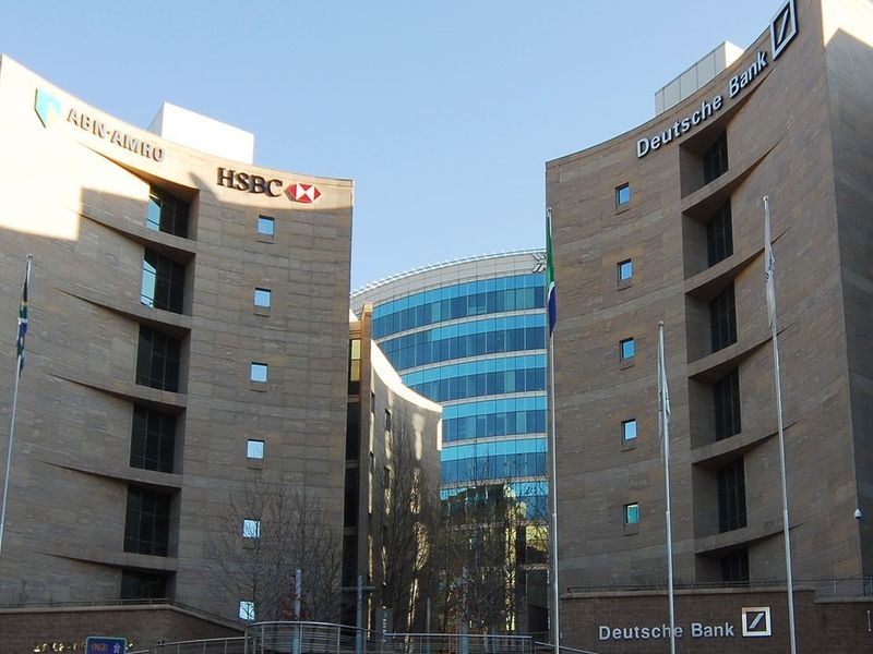 A modern commercial office complex featuring stone-clad curved facades and a central glass curtain wall structure with prominent corporate signage.