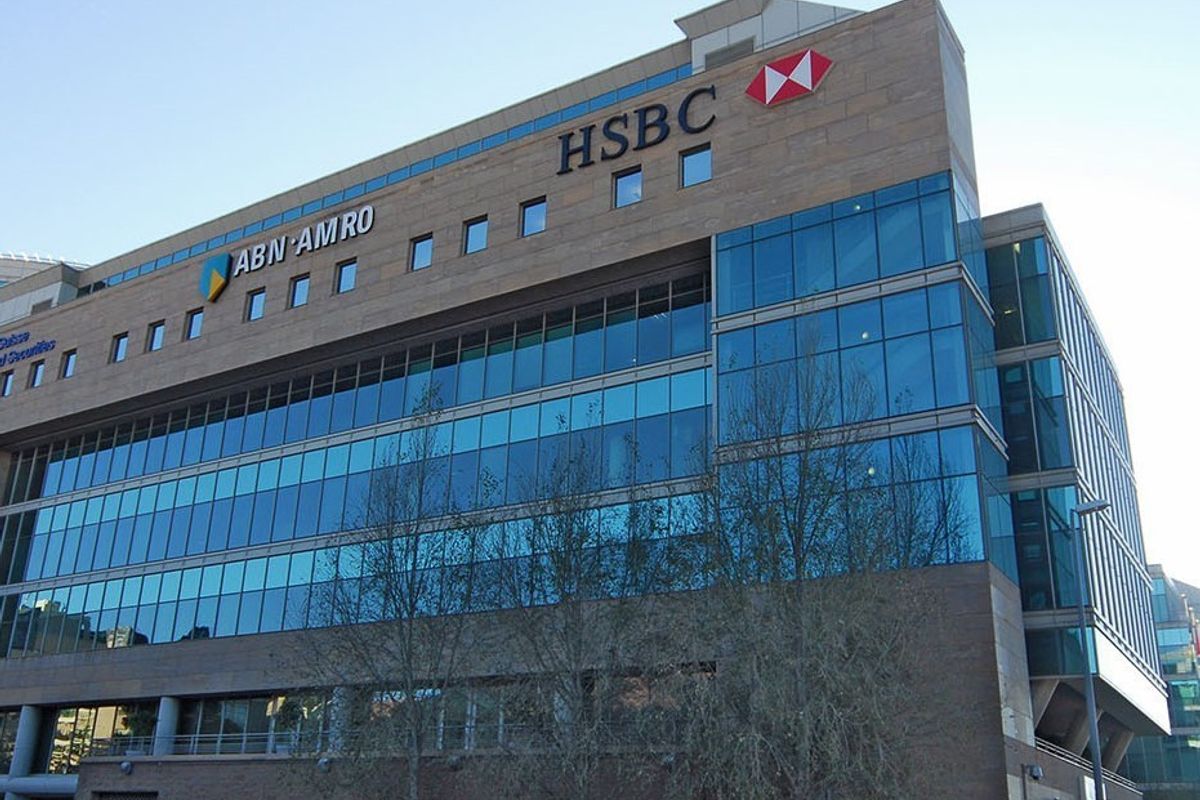 A modern multi-story commercial office building featuring a glass curtain wall facade and stone cladding with prominent corporate signage.
