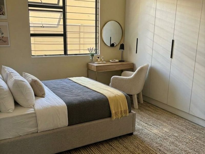 A well-lit bedroom featuring floor-to-ceiling built-in cupboards and a window with security bars, offering a clean and modern aesthetic.